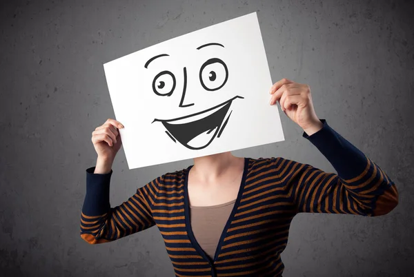 Woman holding a cardboard with smiley face on it in front of her — Stock Photo, Image