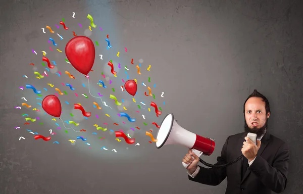 Young guy having fun, shouting into megaphone with balloons — Stock Photo, Image