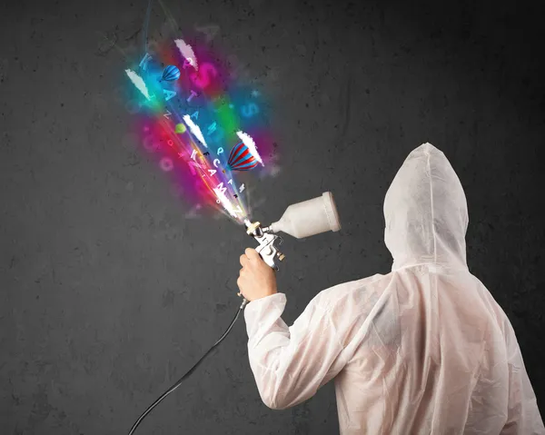 Worker with airbrush and colorful abstract clouds and balloons — Stock Photo, Image