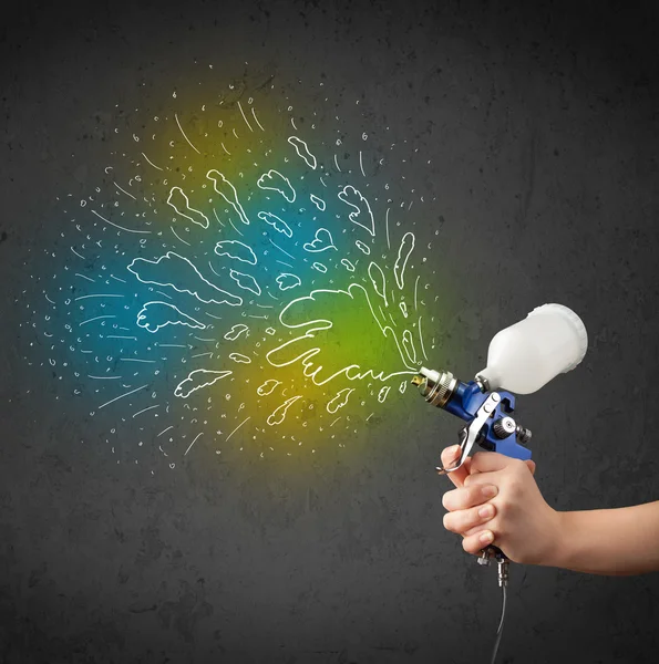 Worker with airbrush gun paints colorful lines and splashes — Stock Photo, Image