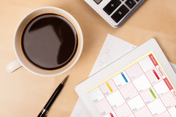 Tablet PC que muestra el calendario en la pantalla con una taza de café en una d — Foto de Stock