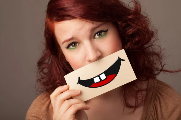 Feliz bonita mujer sosteniendo tarjeta con divertido smiley — Foto de Stock