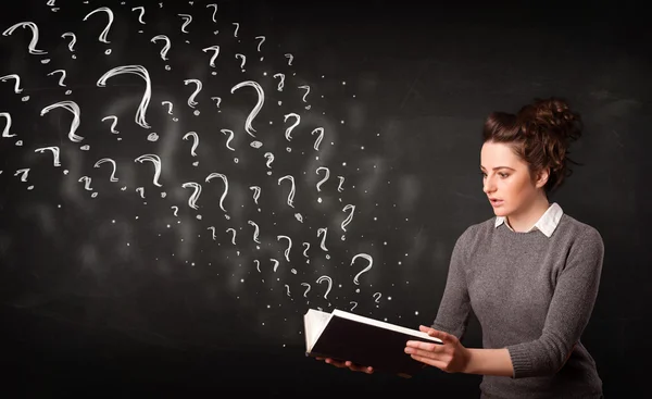 Pretty woman reading a book with question marks coming out from — Stock Photo, Image