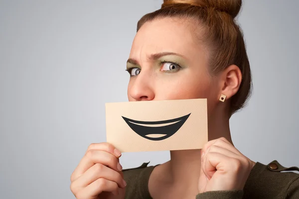 Happy pretty woman holding card with funny smiley — Stock Photo, Image