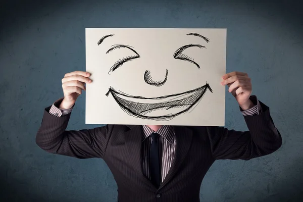 Empresário segurando um papel com rosto sorridente na frente de sua hea — Fotografia de Stock