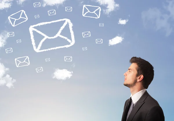 Empresário olhando para o símbolo de correio nuvens no céu azul — Fotografia de Stock