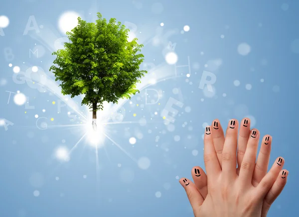 Sorrisi dito felice con albero incandescente magico verde — Foto Stock