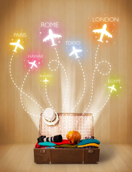 Travel bag with clothes and colorful planes flying out — Stock Photo, Image