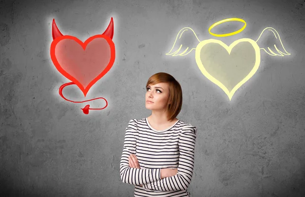 Woman standing between the angel and devil hearts — Stock Photo, Image