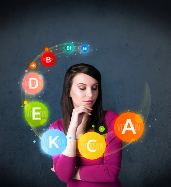 Young woman thinking with vitamins circulation around her head — Stock Photo, Image