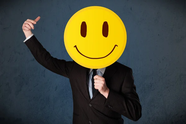 Empresário segurando um emoticon rosto sorridente — Fotografia de Stock
