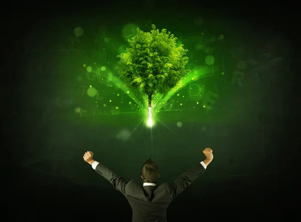 Hombre de negocios haciendo gestos frente a un árbol brillante —  Fotos de Stock