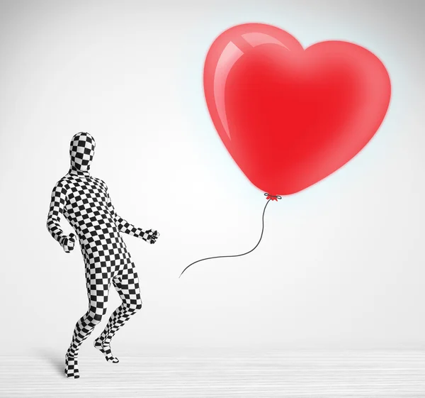 Lindo tipo en traje de cuerpo morpsuit mirando un corazón en forma de globo —  Fotos de Stock