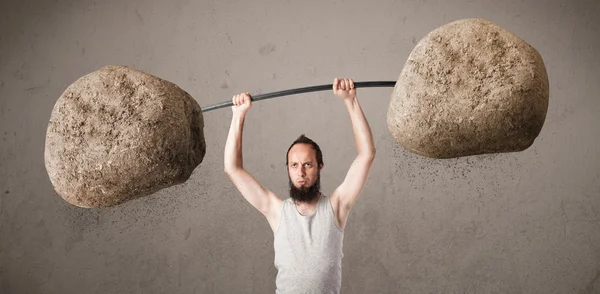 Skinny guy lifting large rock stone weights — Stock Photo, Image