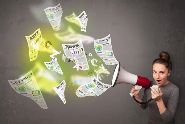 Girl yelling into loudspeaker and newspapers fly out — Stock Photo, Image