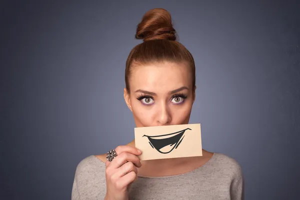 Felice ragazza carina in possesso di carta con divertente disegno smiley — Foto Stock