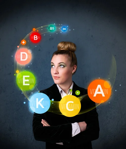 Young woman thinking with vitamins circulation around her head — Stock Photo, Image