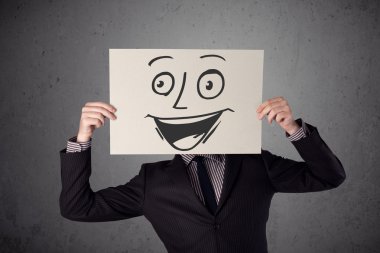 empresario sosteniendo una cartulina con cara sonriente en él en frente