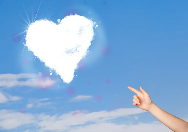 Hand zeigt auf weiße Herzwolke am blauen Himmel — Stockfoto