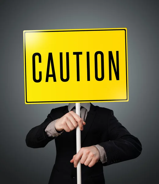 Businessman holding a caution sign — Stock Photo, Image