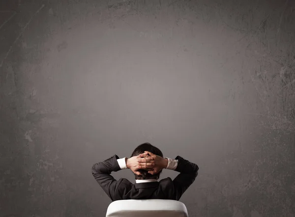 Businessman sitting in front of a wall with copy space — Stock Photo, Image