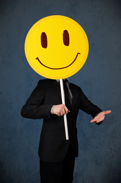 Podnikatel drží smajlík tvář emotikon — Stock fotografie