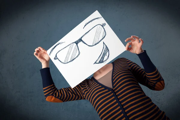 Woman holding a paper with smiley face in front of her head — Stock Photo, Image