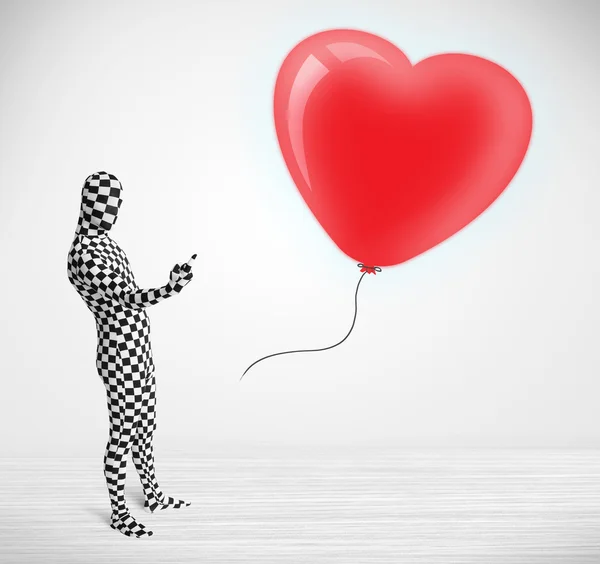 Bonito cara em terno morpsuit corpo olhando para um coração em forma de balão — Fotografia de Stock