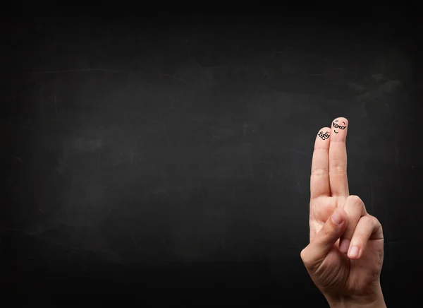 Happy smiley fingers looking at empty black chalboard — Stock Photo, Image