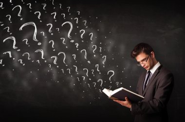 Genç adam içinden soru işaretleri çıkan bir kitap okuyor.