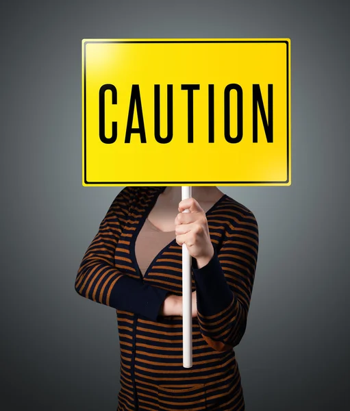 Young woman holding a caution sign — Stock Photo, Image