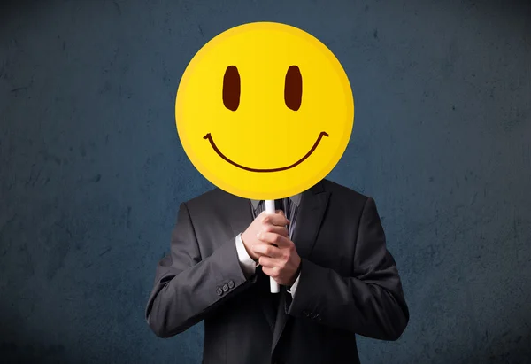 Empresario sosteniendo un emoticono sonriente —  Fotos de Stock
