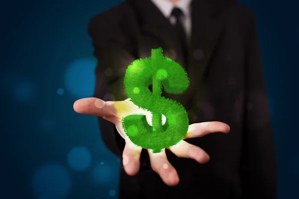 Young businessman presenting green glowing dollar sign — Stock Photo, Image