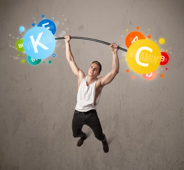 Muscular man lifting colorful vitamin weights — Stock Photo, Image