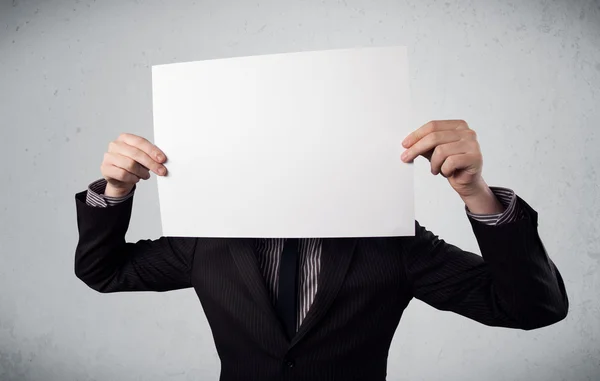 Businessman holding in front of his head a paper with copy space — Stock Photo, Image