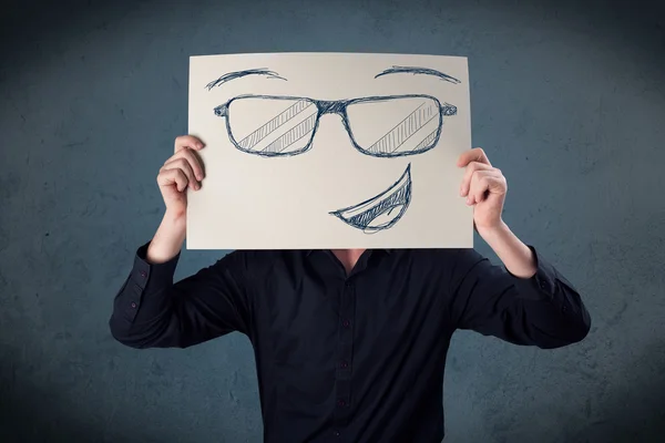 Empresario sosteniendo un papel con la cara sonriente delante de su hea —  Fotos de Stock