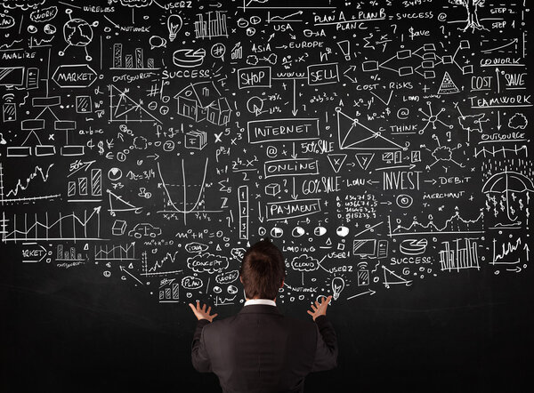 Бизнесмен, стоящий перед нарисованными картами на доске