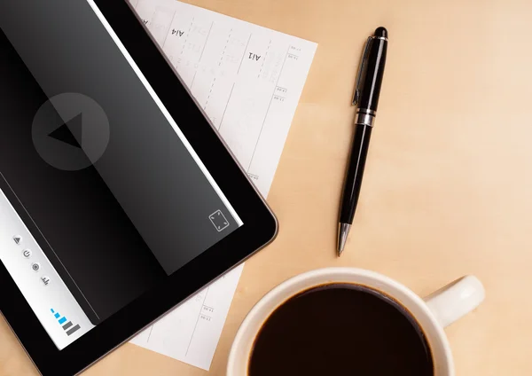 Tablet pc showing media player on screen with a cup of coffee on — Stock Photo, Image