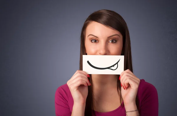 Chica bastante joven sosteniendo la tarjeta blanca con dibujo sonrisa — Foto de Stock