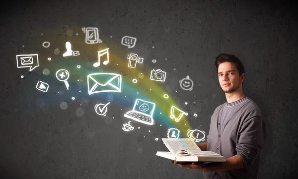 Young guy reading a book with multimedia icons coming out of the — Stock Photo, Image