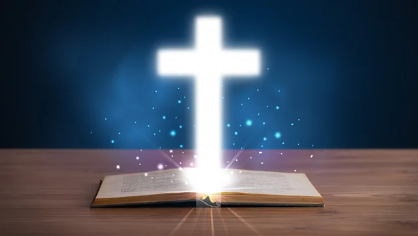 Open holy bible with glowing cross in the middle — Stock Photo, Image