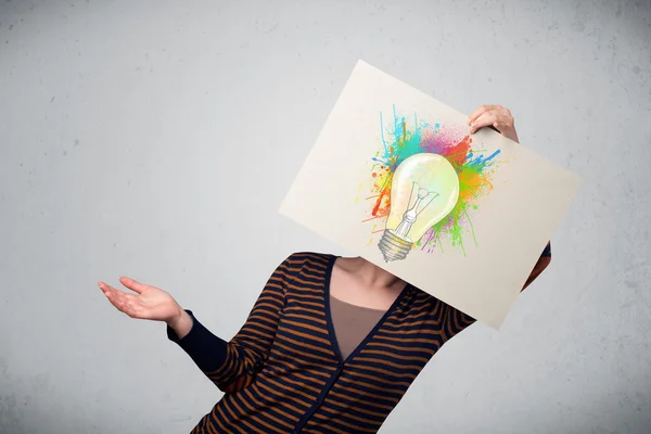 Woman holding a cardboard with paint splashes and lightbulb in f — Stock Photo, Image