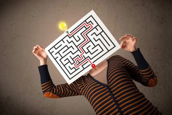 Woman holding a paper with a labyrinth on it in front of her hea — Stock Photo, Image