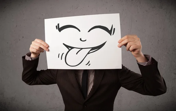 Geschäftsmann hält Papier mit lustigem Smiley-Gesicht vor sich — Stockfoto