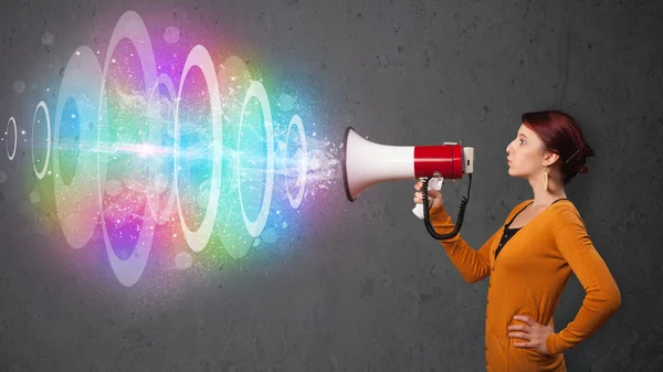 Young girl yells into a loudspeaker and colorful energy beam com — Stock Photo, Image