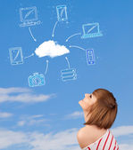 Příležitostná dívka při pohledu na cloud výpočetní koncept na modré obloze