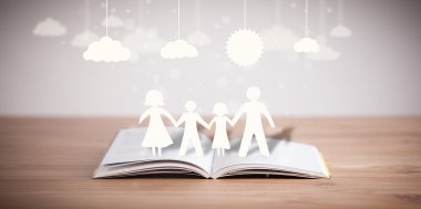 Ailenin karton figürleri açık bir kitabın üzerinde.