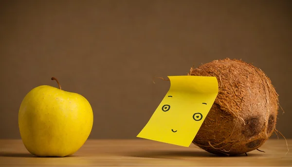 Coconut with post-it note looking at apple — Stock Photo, Image