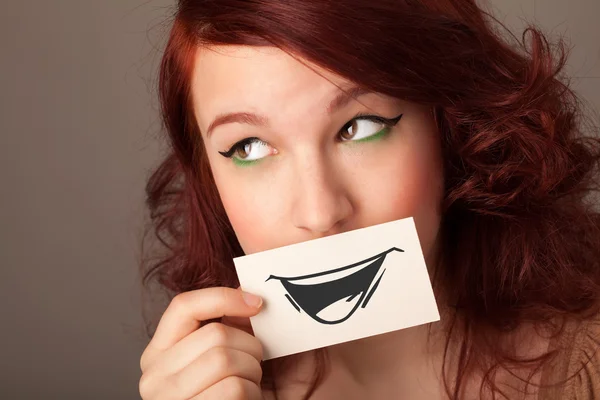 Happy cute girl holding paper with funny smiley drawing — Stock Photo, Image