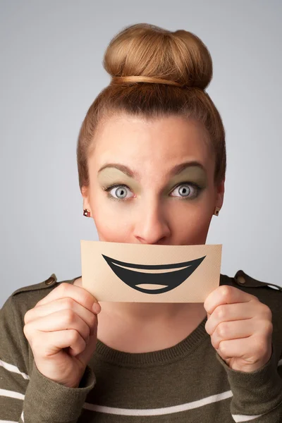 Happy pretty woman holding card with funny smiley — Stock Photo, Image